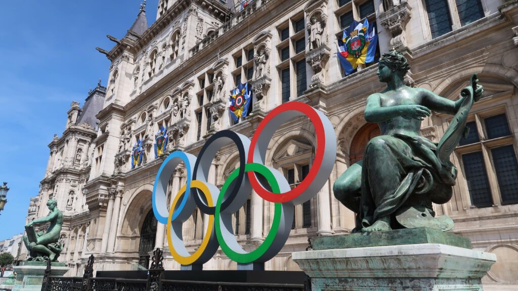 JO de Paris 2024, anneaux olympiques, célèbre logo symbole des jeux olympiques, devant la façade de la mairie / hôtel de ville de Paris, avec une statue